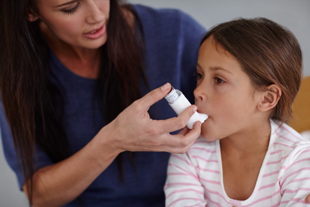 Breathe in, honey. Shot of a caring mother giving her daughter an asthma pump at home.