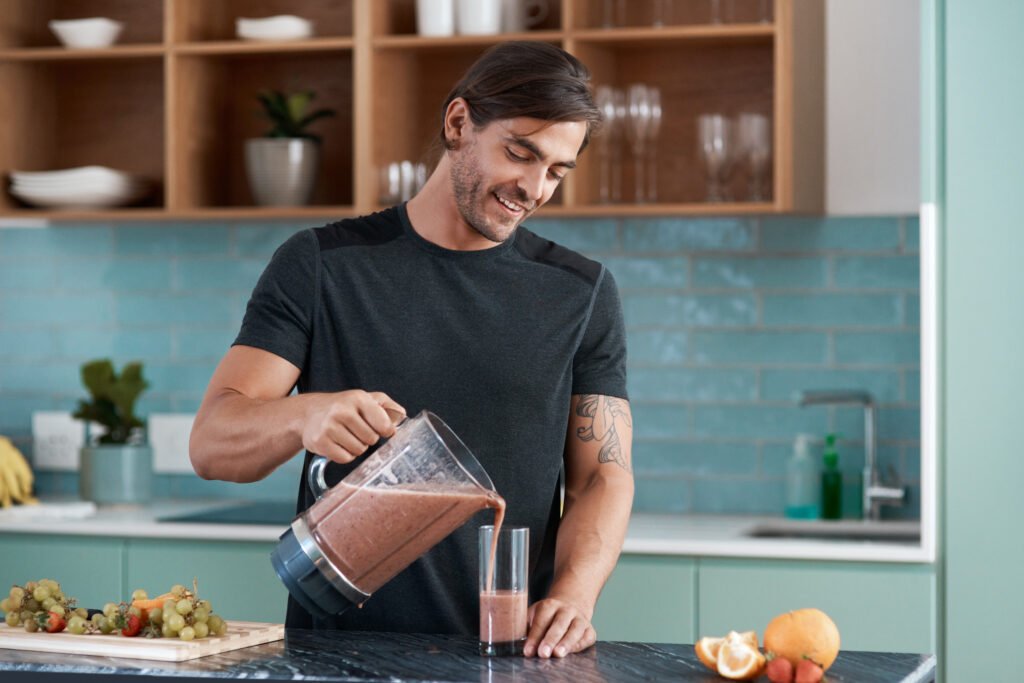 Cropped shot of a handsome young man making smoothies in his kitchen at home.