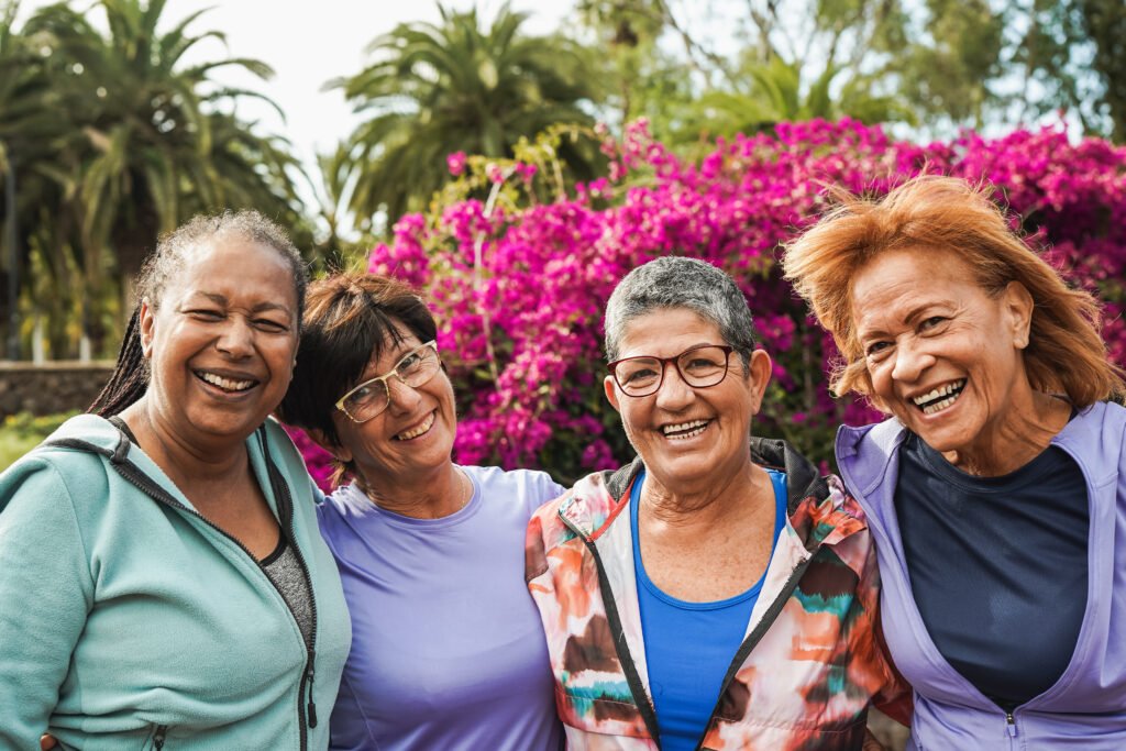 Group of happy senior women hugging each other and smiling on camera at city park after sport workout - Joyful elderly people and healthy lifestyle concept