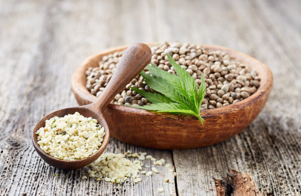 Organic hulled hemp seeds with plant on wooden old board