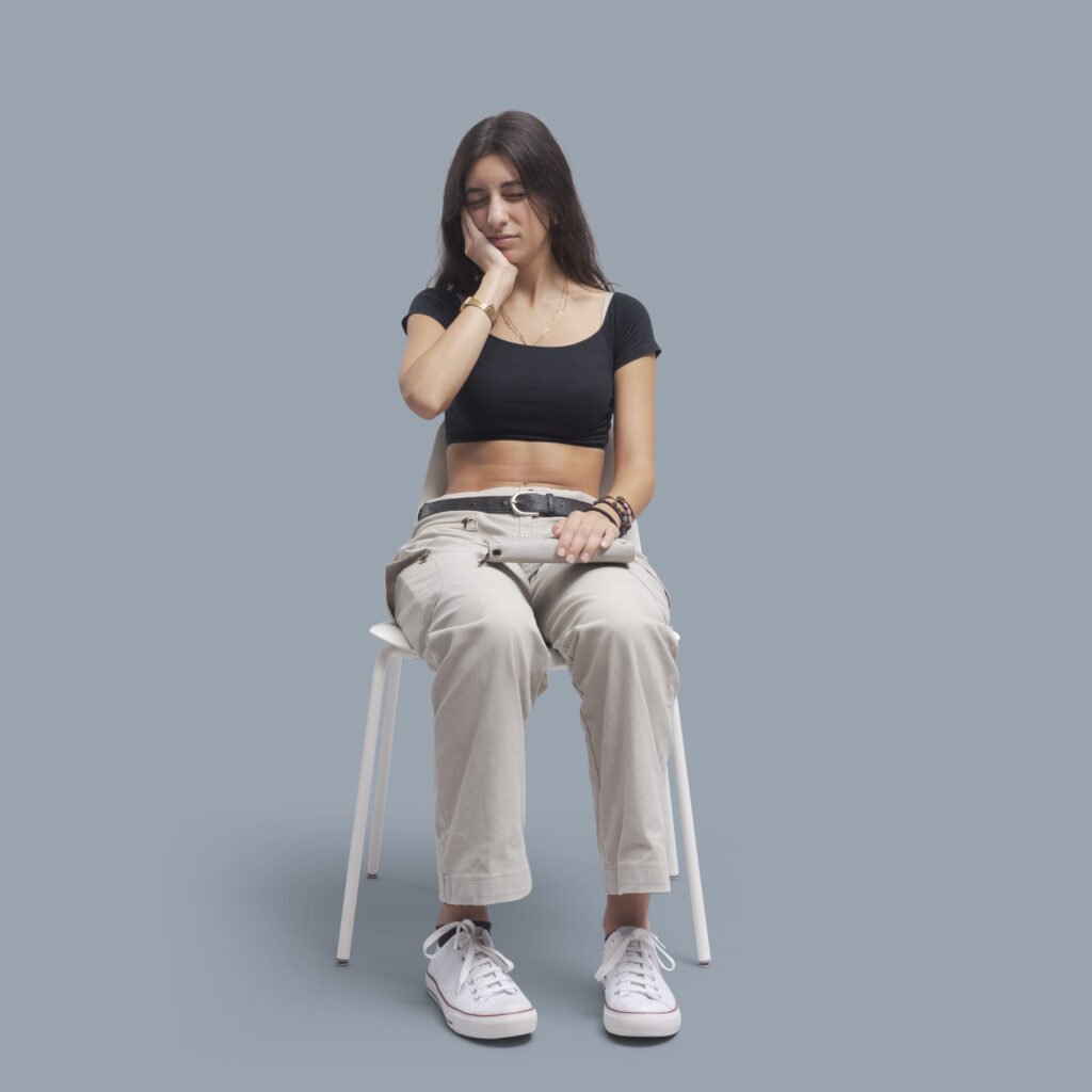 Woman sitting on a chair and touching her cheek.