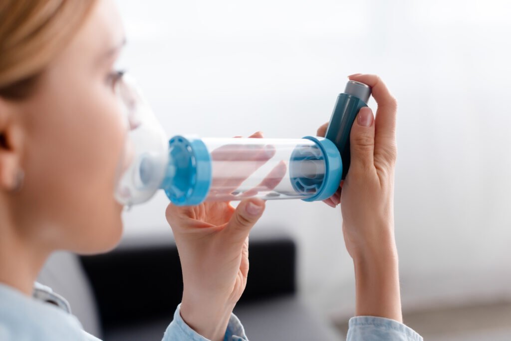 selective focus of asthmatic woman using inhaler with spacer.