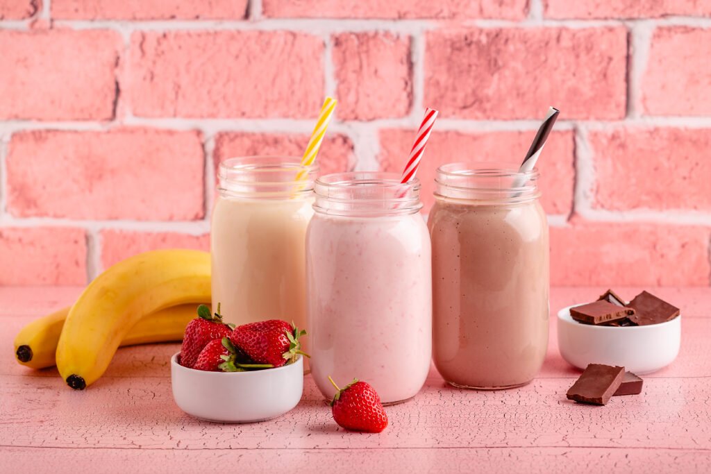 Set of strawberry banana and chocolate milkshakes in the glass jars