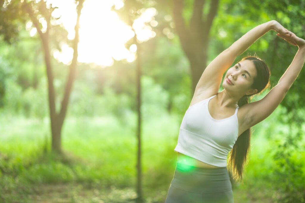 Young asian woman practicing yoga in green environment.female happiness. blurred background.Healthy lifestyle and relaxation concept