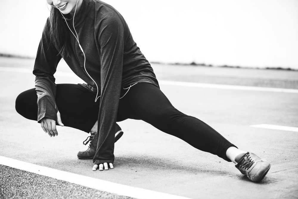 girls streching her leg middle in the road . showing phycally fit women.