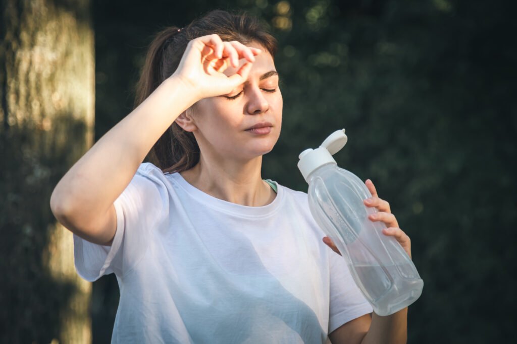 Attractive young woman drinks water after jogging in the park to save itself from Dehydration.