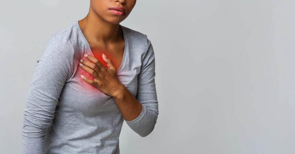 Cropped of afro woman suffering from acid reflux or shortness of breath, symptomatic indigestion or gastritis disease.