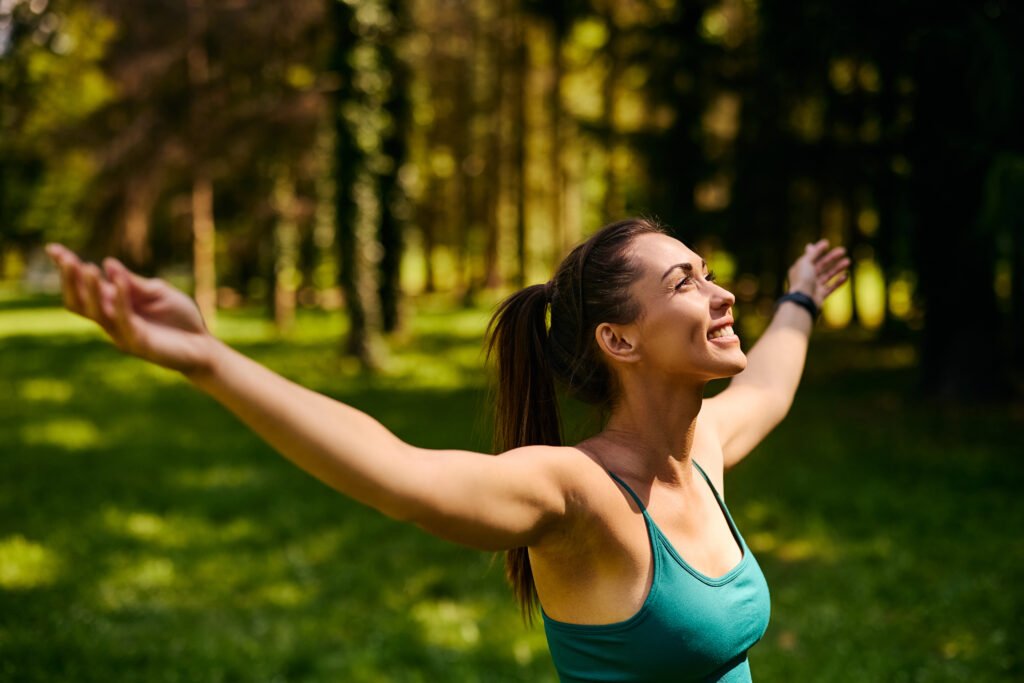 Happy athletic woman with arms outstretched enjoying in nature.