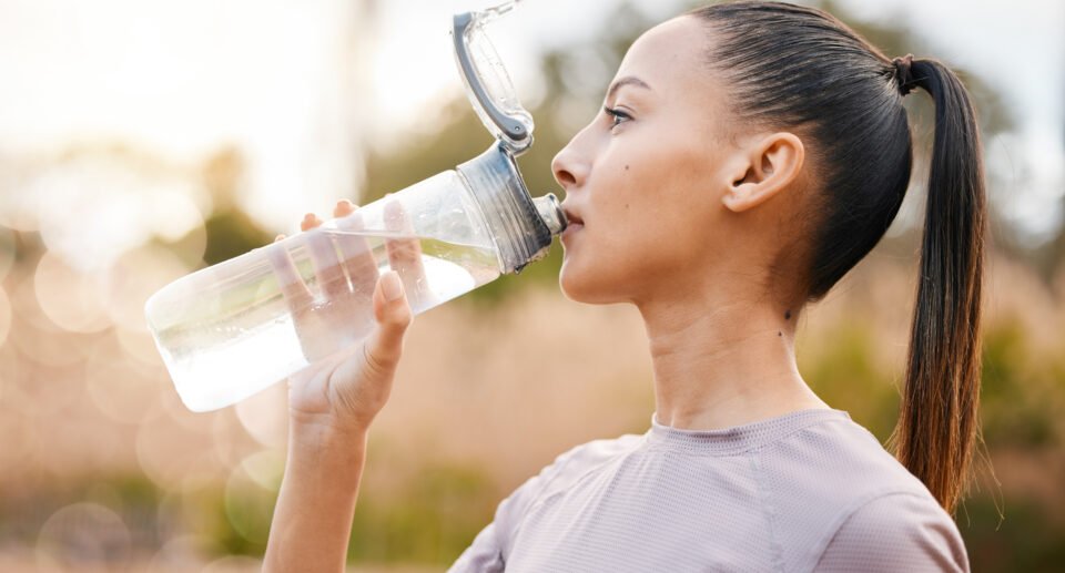 Fitness, health and woman drinking water in nature after exercise to overcome from Dehydration.