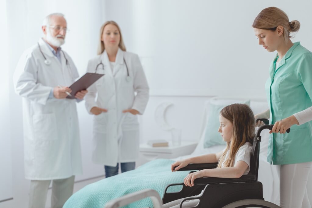 Sick little girl on a wheelchair taken care by the nurse for the surgery