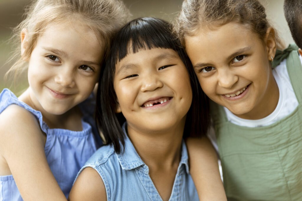 Group of cute asian and caucasian girls having fun in the park showing different dental conditions.