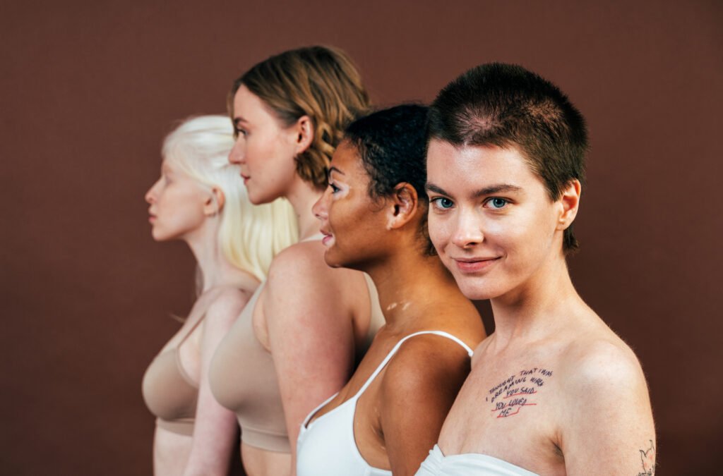 Group of multiethnic women with different kind of skin posing together in studio. Concept about breast cancer positivity and self acceptance.