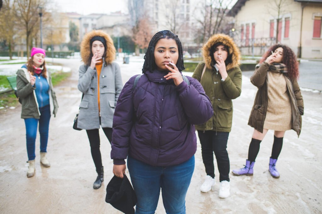 group of young multiracial women smoking cigarette in the street may couses shortness of breath.