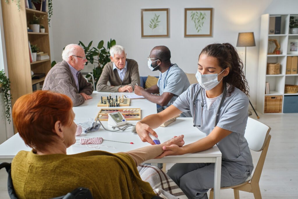 Nurse taking blood test from senior woman during medical exam in nursing home