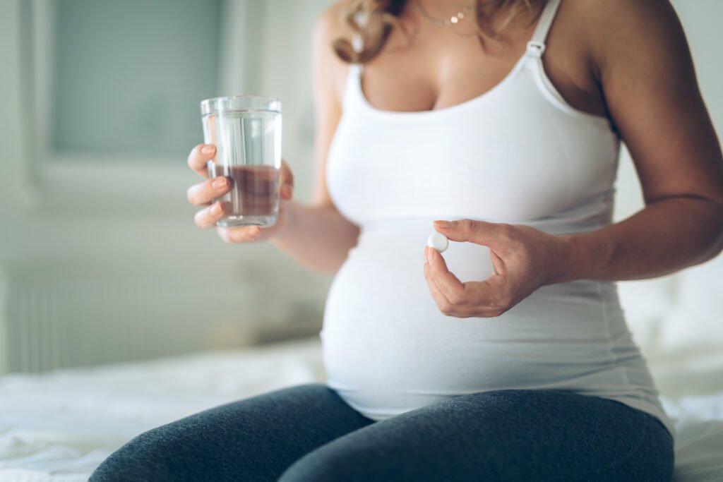 Picture of pregnant woman taking medication pills at home due to hormonal imbalance.