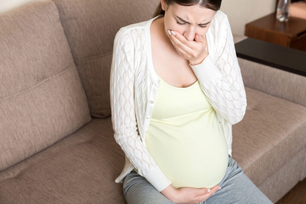 Pregnancy Morning Sickness. Pregnant Woman Having Nausea Feeling Bad becouse of hormonal imbalance in Sofa at the Home.