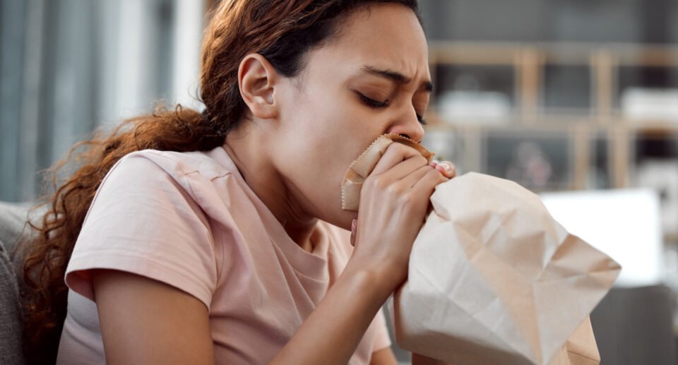 Shot of a young woman experiencing Shortness of breath after eating while sitting on the sofa at home.