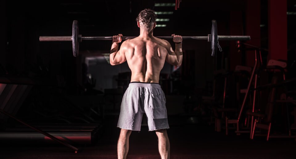 Sports man raises the bar, to do Back workout with barbell in the gym, the concept of sport.