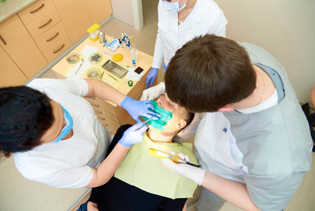 Team of dentists treats teeth to patient in dental clinic.