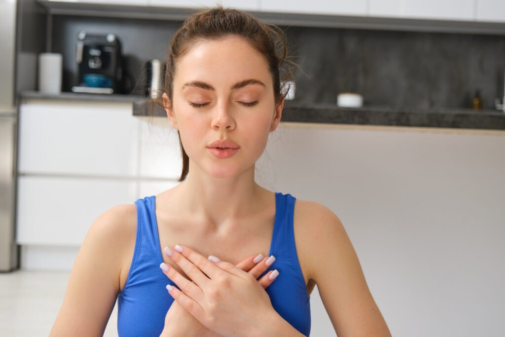 Woman practicing yoga and meditation at home sitting in lotus pose on yoga mat, relaxed with closed eyes to fix shoetness of breath.